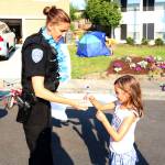Neighborhood Resource Officer Deana Lansing hands Isabella Adkins, 6, a pen during a community cookout in the 13600 block of 116th Avenue Northeast in Kirkland on National Night Out Tuesday. Megan Campbell/staff photo
