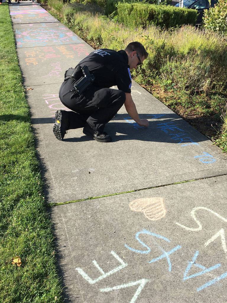 A Kirkland police officer writes a message on the sidewalk in front of Google. Courtesy of Sarah Franklin