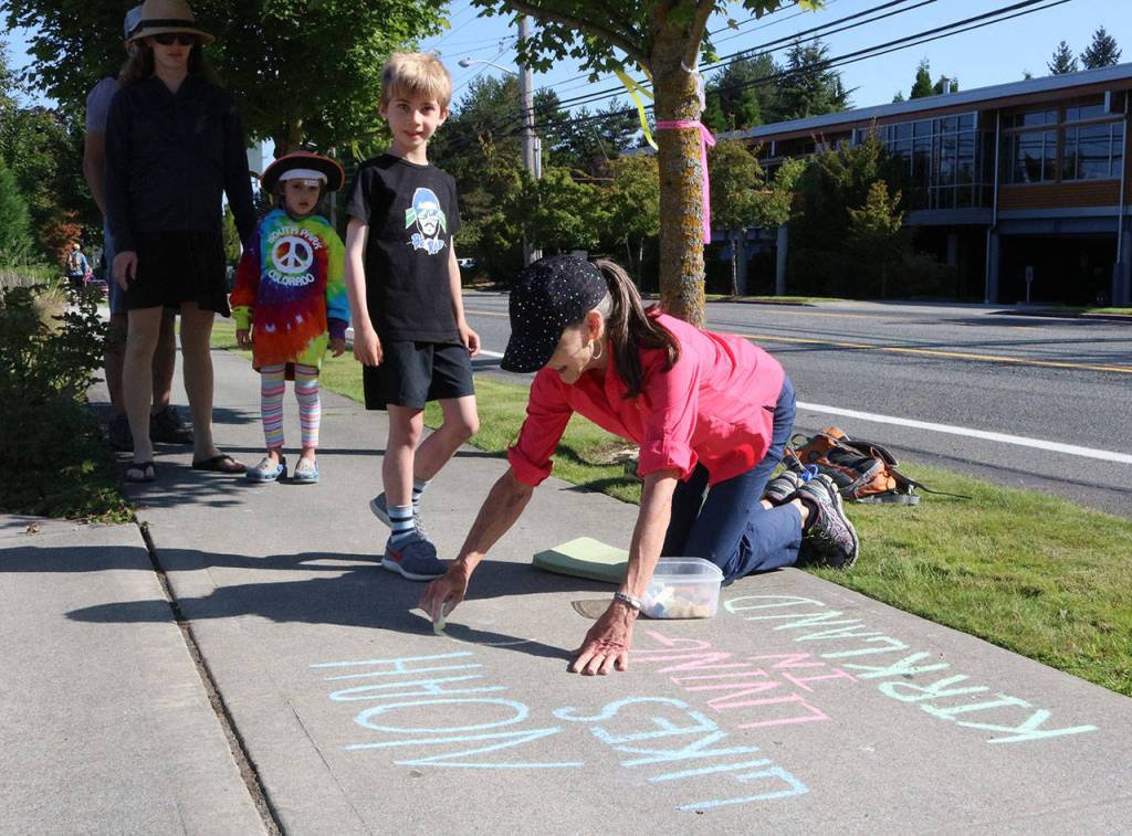 Kirkland resident Janetmarie Wolfe writes a message on the sidewalk in front of Google. Samantha Pak, Kirkland Reporter