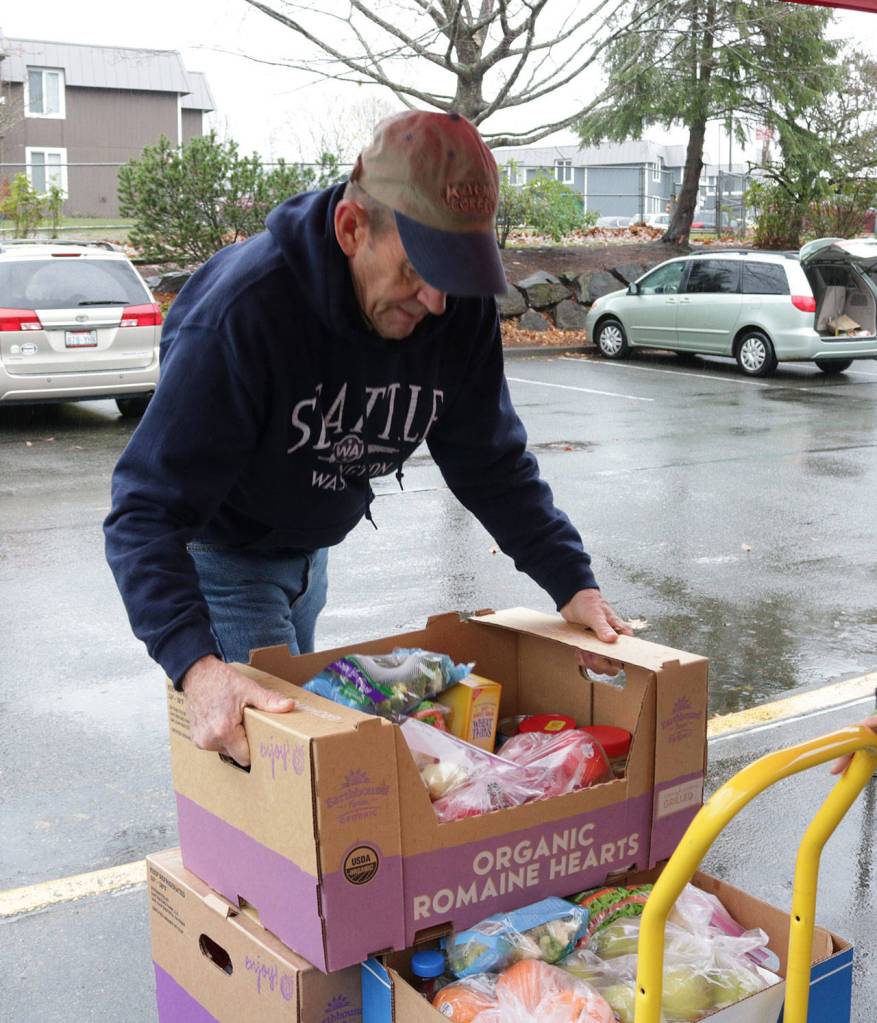 A volunteer loads food boxes onto a cart. Samantha Pak, Kirkland Reporter