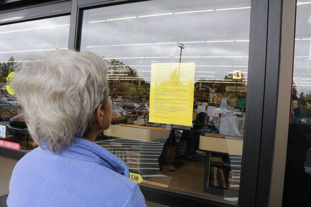 Kirkland resident Helge Nason reads the notice Bridle Trails Red Apple store owner Lori Croshaw posted about the store closure. Nason was sad to hear the store was closing its doors and spoke of the stores amazing customer service. Megan Campbell, Kirkland Reporter