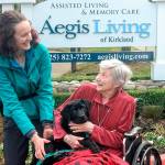 Lindy Langum, the Summit Assistance Dog trainer, helps a senior from Aegis Living hold one of the puppies-in-training. Courtesy of Aegis Living.