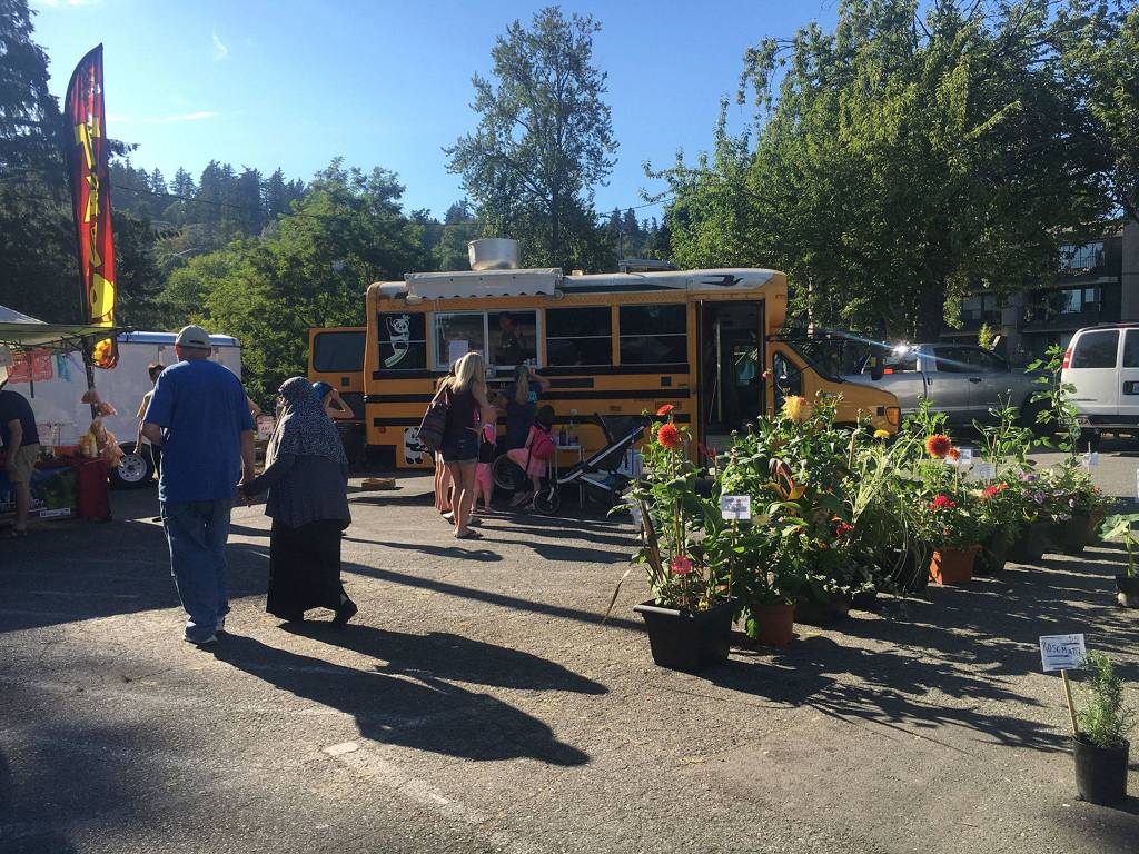Market goers walk by a farm stand and the Panda Dimsum food truck. Katie Metzger/staff photo