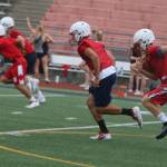 Juanita High players roll up field while the Rebel cheerleaders practice in the background. Andy Nystrom/ staff photo