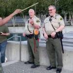 A man dangles a doughnut in front of police officers. (Screen grab from video courtesy of Bennett Haselton)