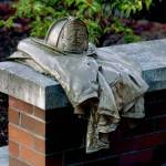 A bronze firefighters helmet and turnout jacket is mounted on a bench at a Gary Parks memorial outside the Everett Community College library. (Dan Bates / Herald file)